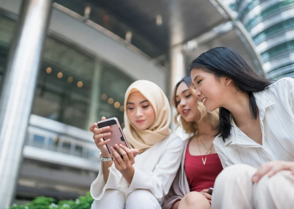 Three young people look at a phone. Multi-channel marking is a key tool in any business.